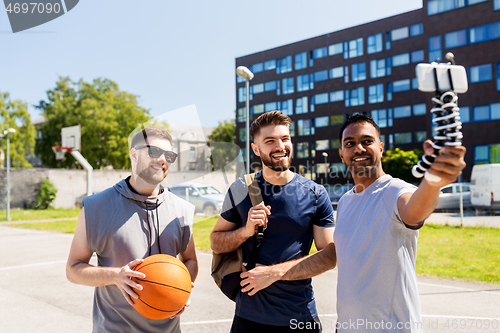 Image of happy men taking selfie at basketball playground