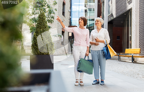 Image of senior women with shopping bags walking in city