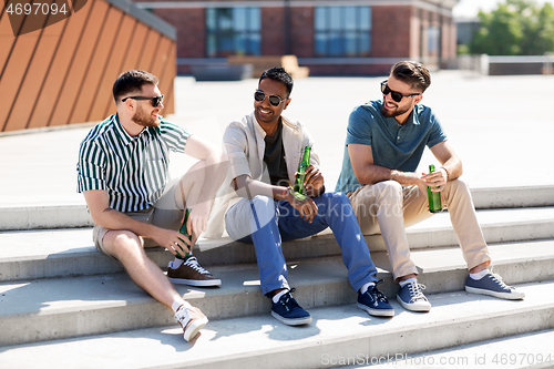 Image of happy male friends drinking beer on street