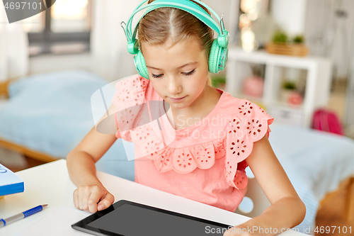 Image of girl in headphones with tablet computer at home