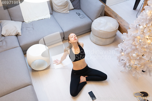 Image of Beautiful blonde woman doing home workout indoors. Woman practice yoga at home. Fit girl using workout tutorials for healthy active lifestyle. Woman using quarantine for home workouts.