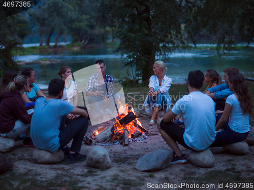 Image of young friends relaxing around campfire