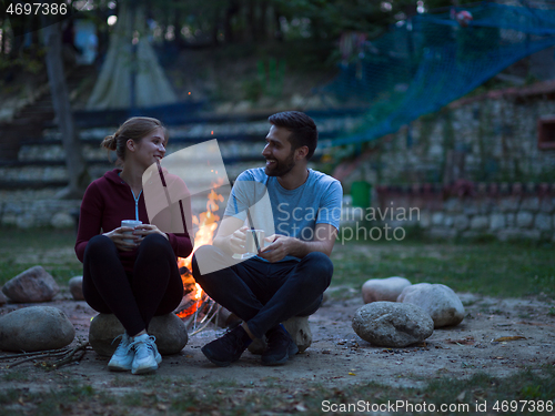 Image of couple sitting around the campfire at evening