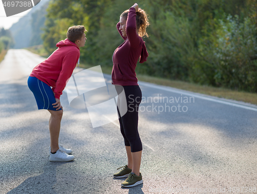 Image of young couple warming up and stretching on a country road