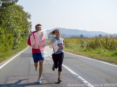 Image of young couple jogging along a country road