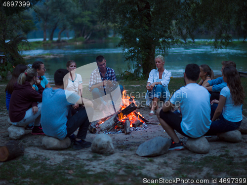 Image of young friends relaxing around campfire