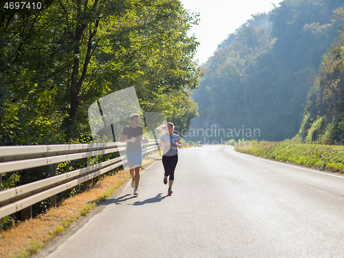 Image of young couple jogging along a country road