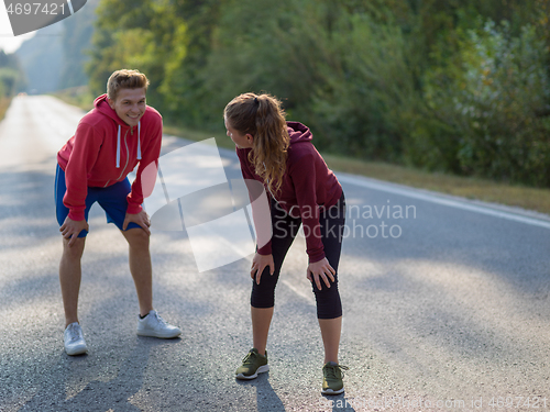 Image of young couple warming up and stretching on a country road