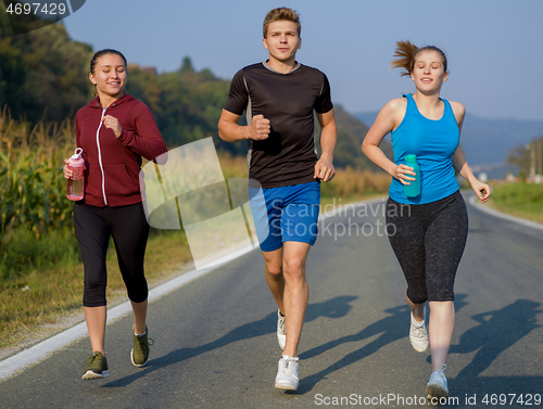 Image of young people jogging on country road