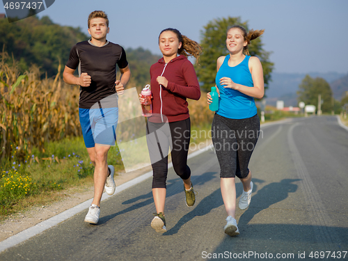 Image of young people jogging on country road