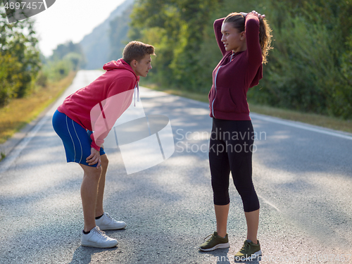 Image of young couple warming up and stretching on a country road