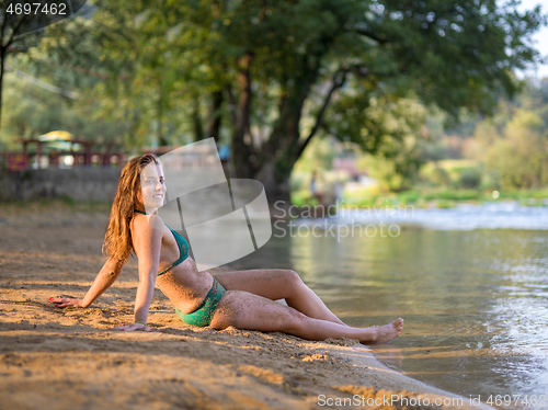 Image of girl in a green bikini relaxing on the riverbank