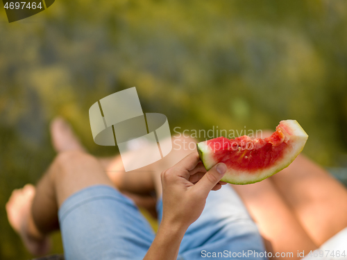 Image of Couple eating watermelon enjoying picnic time