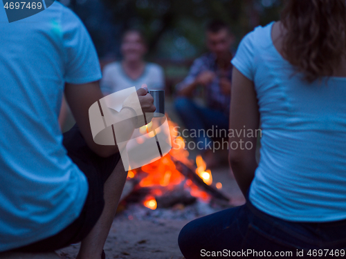 Image of young friends relaxing around campfire