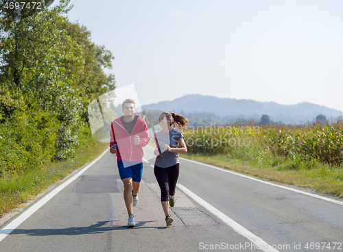 Image of young couple jogging along a country road