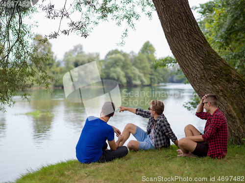 Image of men sitting on the bank of the river