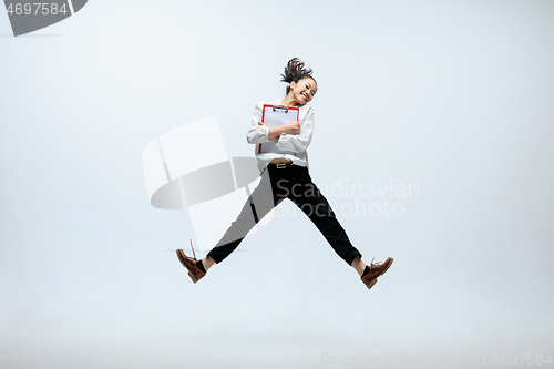 Image of Woman working at office and jumping isolated on studio background