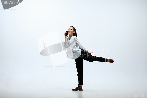 Image of Woman working at office and jumping isolated on studio background