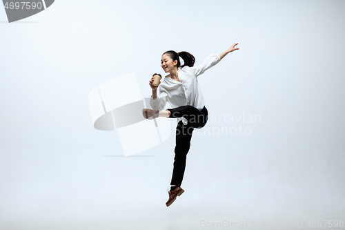 Image of Woman working at office and jumping isolated on studio background