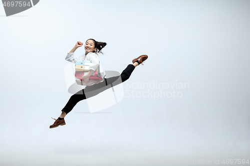 Image of Woman working at office and jumping isolated on studio background