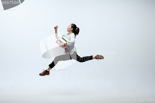 Image of Woman working at office and jumping isolated on studio background