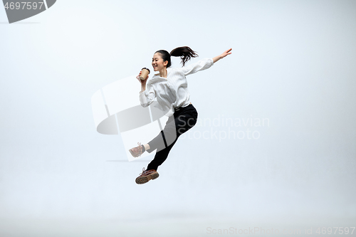 Image of Woman working at office and jumping isolated on studio background