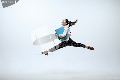 Image of Woman working at office and jumping isolated on studio background
