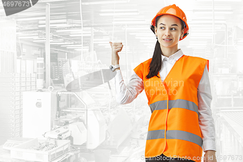 Image of Destroying gender stereotypes. Female builder standing against industrial background