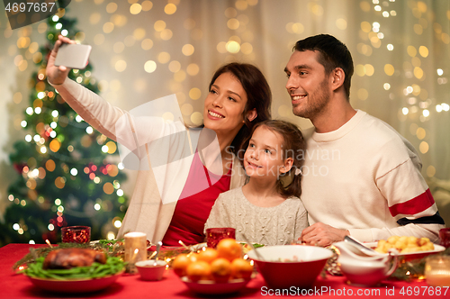 Image of happy family taking selfie at christmas dinner