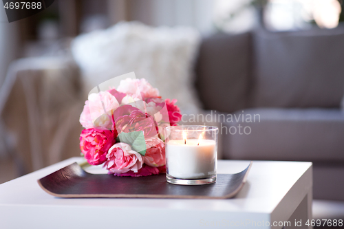 Image of burning fragrance candle and flower bunch at home