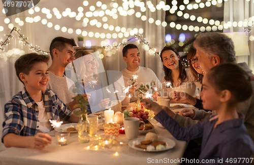 Image of family with sparklers having dinner party at home