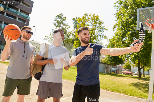 Image of happy men taking selfie on basketball playground