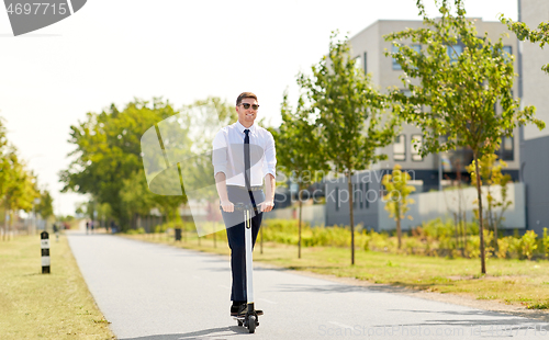 Image of young businessman riding electric scooter in city