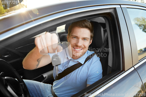Image of smiling man or driver with key sitting in car