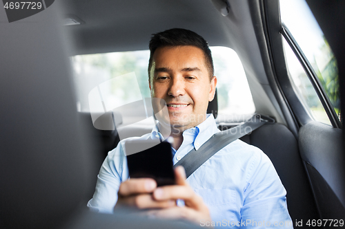 Image of passenger or businessman using smartphone in car