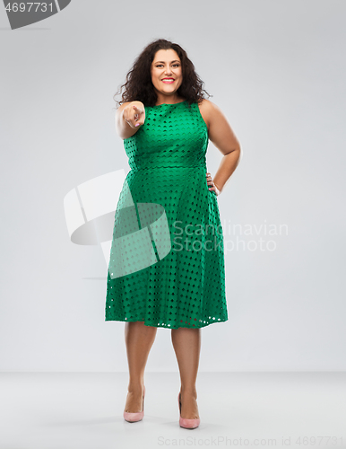 Image of woman in green dress pointing finger to camera