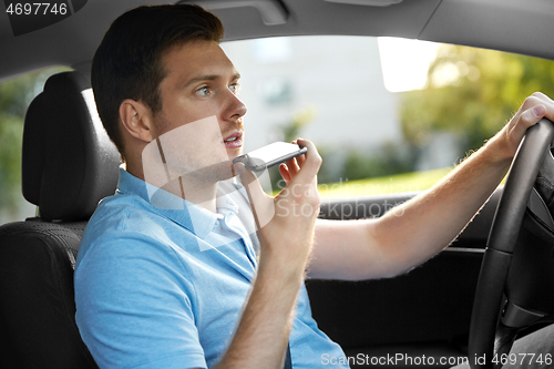 Image of man driving car and recording voice by smartphone