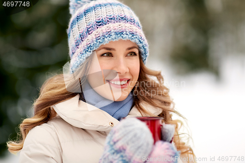 Image of happy young woman with tea cup outdoors in winter