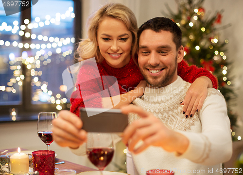 Image of happy couple taking selfie at christmas dinner