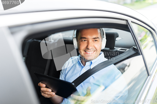 Image of passenger with headphones using tablet pc in car