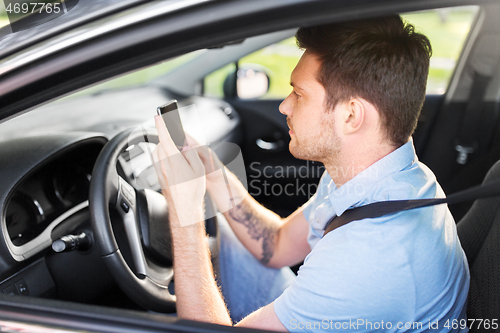 Image of man driving car and using smartphone