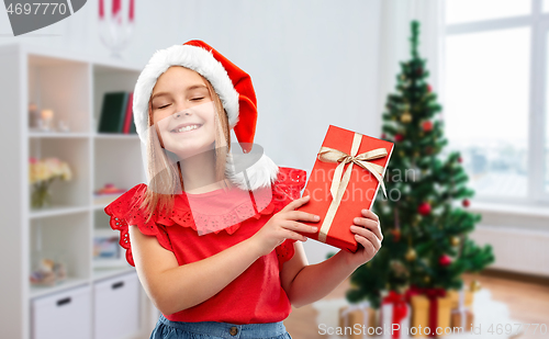 Image of girl in santa hat with christmas gift at home