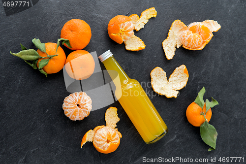 Image of glass bottle of fruit juice and peeled mandarins