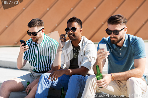 Image of men with smartphones drinking beer on street