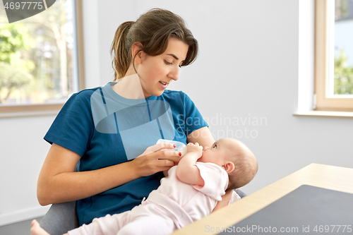 Image of mother feeding baby daughter with milk formula