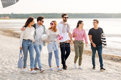 Image of happy friends walking along summer beach