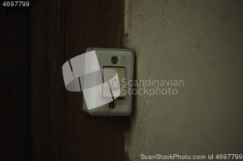 Image of Old electric door bell fitting on a wooden door