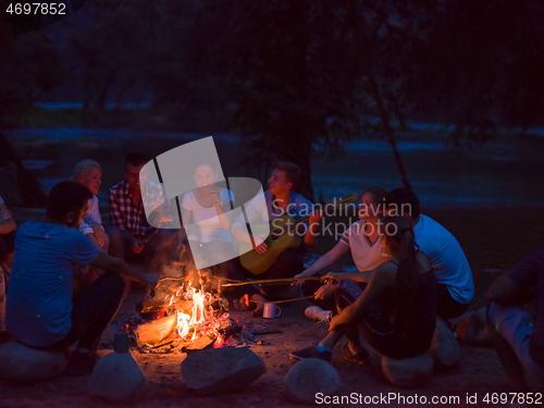 Image of young friends relaxing around campfire