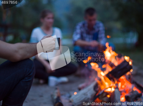 Image of young friends relaxing around campfire