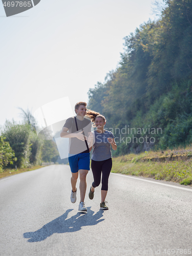 Image of young couple jogging along a country road